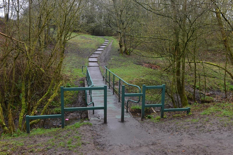 Pass through the gate onto the roadside path and up the bank, passing the stream on the left. Take the next left onto the tarmac path and stay on this to the junction.