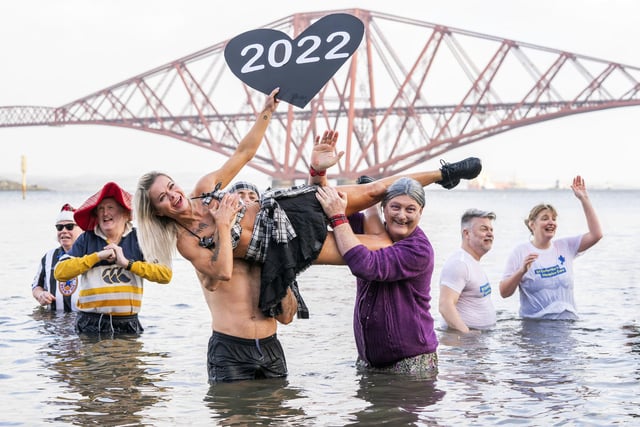 People take part in a New Year's Day dip in front of the Forth Bridge at South Queensferry, Edinburgh. Covid restrictions across Scotland have meant that many new year traditions including the official annual Loony Dook have been cancelled. Picture date: Saturday January 1, 2022. PA Photo. Photo credit should read: Jane Barlow/PA Wire