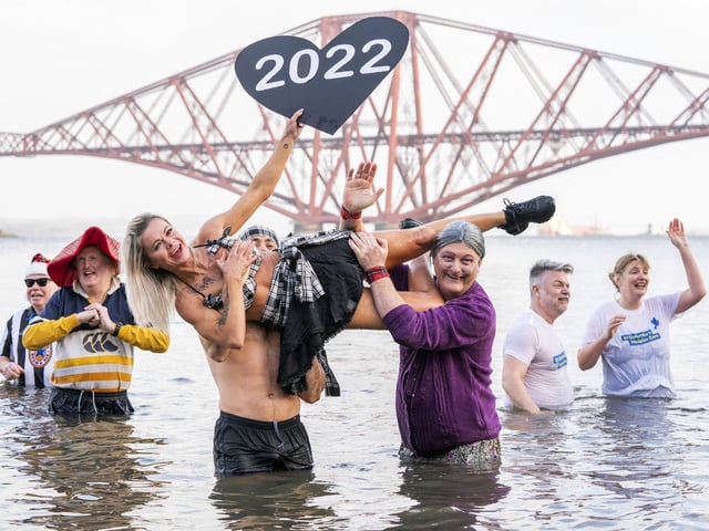 People take part in a New Year's Day dip in front of the Forth Bridge at South Queensferry, Edinburgh. Covid restrictions across Scotland have meant that many new year traditions including the official annual Loony Dook have been cancelled. Picture date: Saturday January 1, 2022. PA Photo. Photo credit should read: Jane Barlow/PA Wire