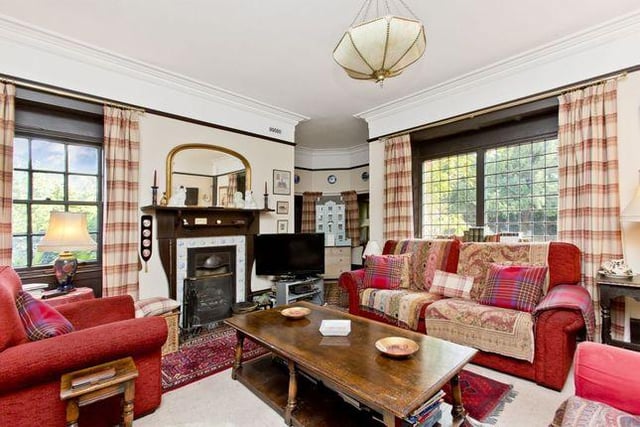 A large family room with a triple-windowed turret, original fireplace, and bespoke-built library shelves