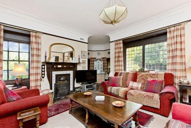 A large family room with a triple-windowed turret, original fireplace, and bespoke-built library shelves