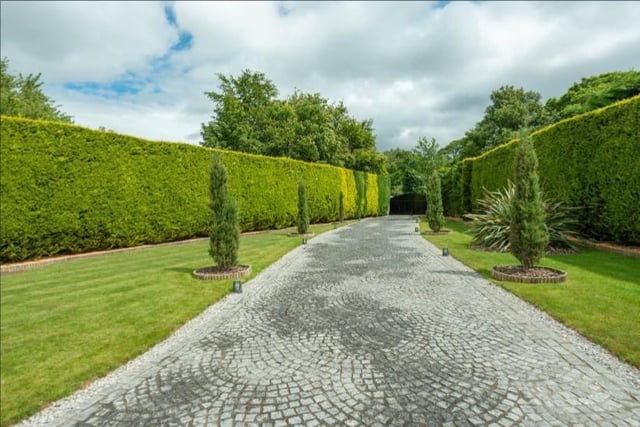 Set behind electronic gates, a granite driveway leads you to the property with lawns and island planting on either side.
Well-maintained landscaped gardens surround the home and there are hedged boundaries for privacy. Image by Rightmove.