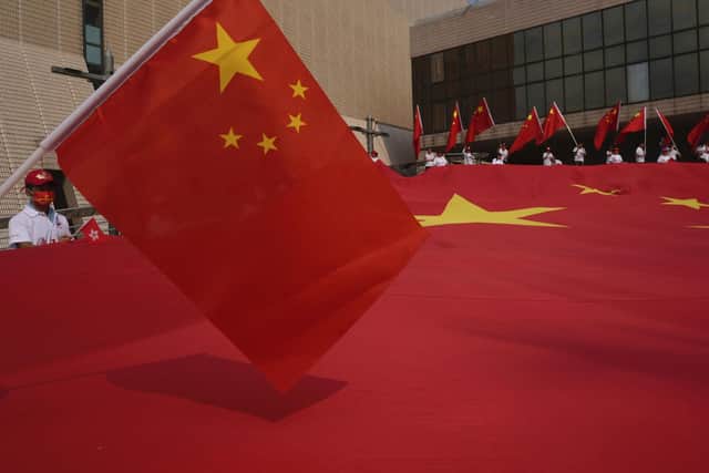 People wave a huge Chinese national flag during a ceremony to mark China's 72nd National Day in Hong Kong Friday, Oct. 1, 2021. (AP Photo/Vincent Yu)