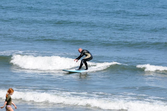 A surfer is enjoying the waves and high temperatures at Seaburn beach.