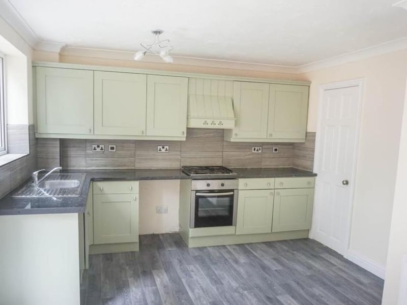 Bright, modern kitchen with a range of wall and base units with complimentary work tops, stainless steel sink and drainer with mixer tap, window bringing in lots of natural light and overlooking the rear garden, hob with extractor hood over and integrated electric oven under, space for white goods, central heating radiator and low maintenance flooring