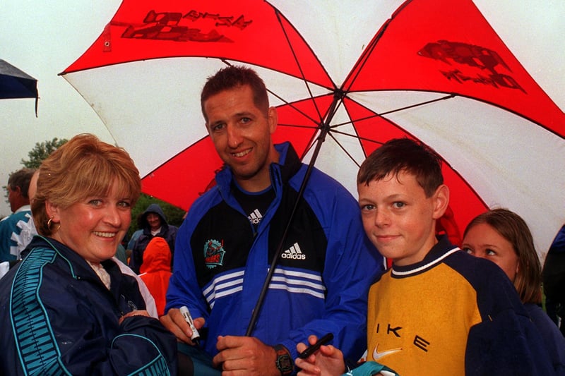 Sheffield Steeler Andre Malo shelters from the rain to sign autographs for fans at the club's Fun Day at the Don Valley Bowl in August 1998