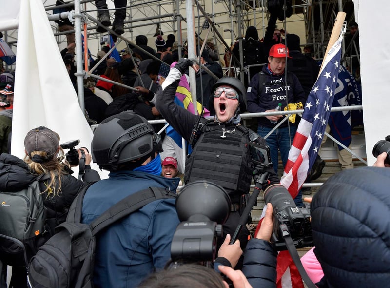 A man calls on people to raid the building as Trump supporters clash with police and security forces as they try to storm the US Capitol in Washington D.C on January 6, 2021. - Demonstrators breeched security and entered the Capitol as Congress debated the a 2020 presidential election Electoral Vote Certification. (Photo by Joseph Prezioso / AFP)