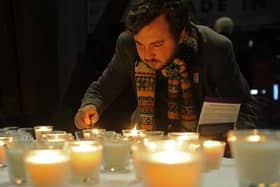 James Collister lights a candle at a candlelit vigil in the Winter Gardens, Sheffield for Holocaust Memorial Day in January 2017