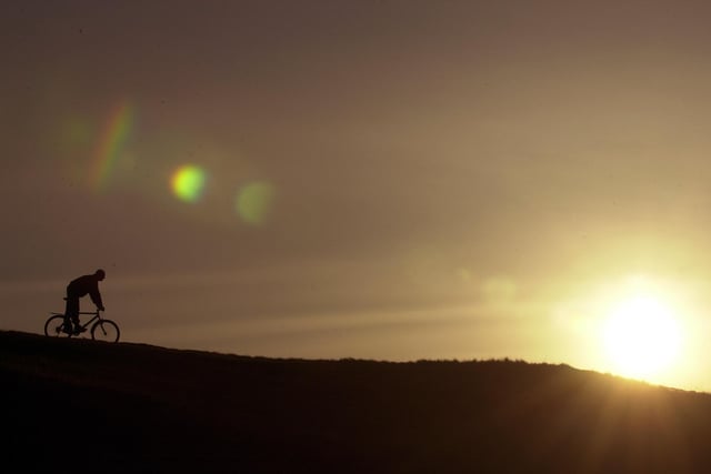 A cyclist makes his way along the top of Salisbury Craggs at sunset.
