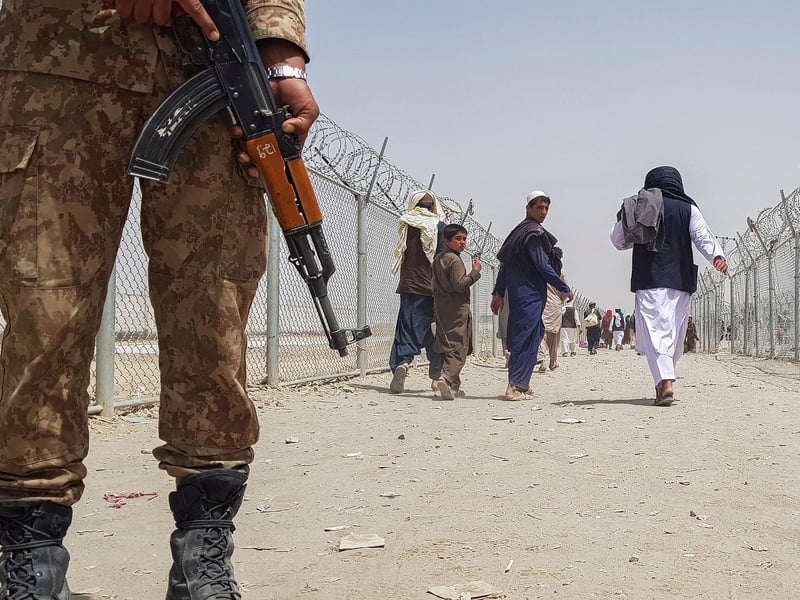 A Pakistani soldier stands guard as stranded Afghan nationals return to Afghanistan at the Pakistan-Afghanistan border crossing point in Chaman