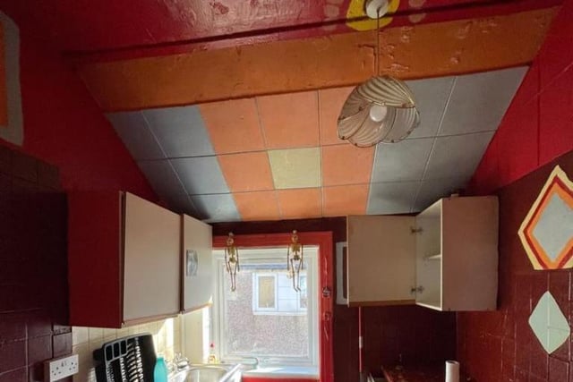 The kitchen has been painted dark red with a colourful ceiling.