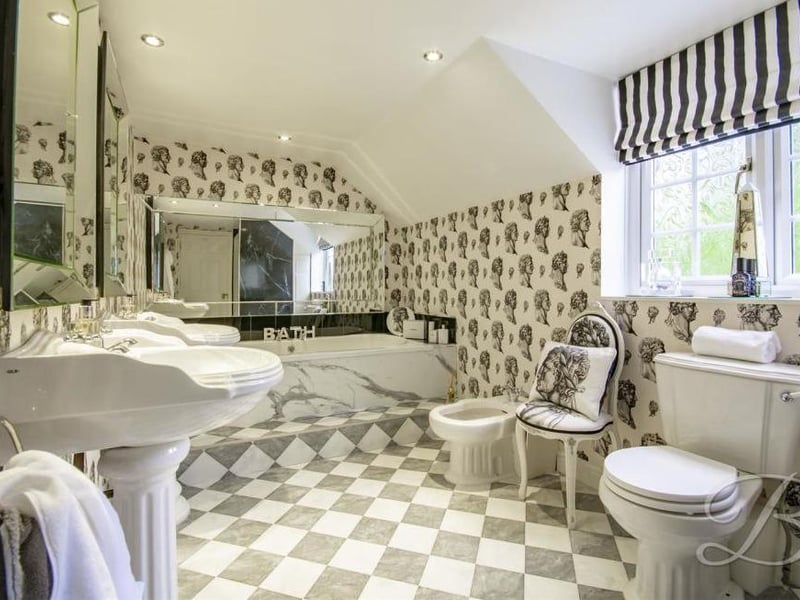 A family bathroom, probably best described as spectacular. It boasts an enclosed shower, bath, two pedestal sinks, central heating, low-flush WC, bidet and opaque window to the side.