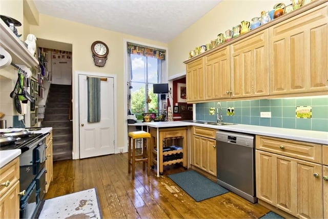 The kitchen has extensive wall and base cabinets, plentiful workspace, decorative tiling, wood floor, an AGA stove, integrated microwave, and a plumbed-in refrigerator.
