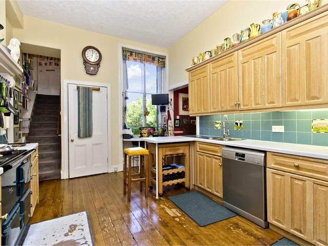 The kitchen has extensive wall and base cabinets, plentiful workspace, decorative tiling, wood floor, an AGA stove, integrated microwave, and a plumbed-in refrigerator.