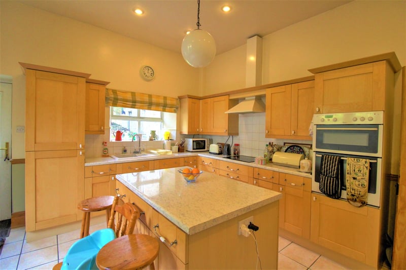 The spacious kitchen which offers a range of pine base and wall units with rolled worktop with tiled splashback.