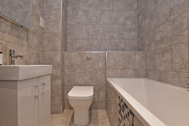 This is the main bathroom, which again is fully tiled and features a panelled bathtub.