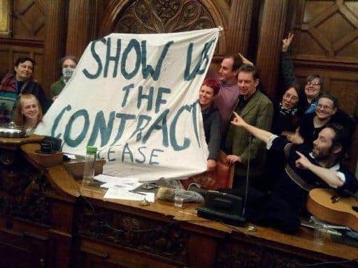 Street tree campaigners inside Sheffield Town Hall holding a banner that reads: "Show us the contract."
