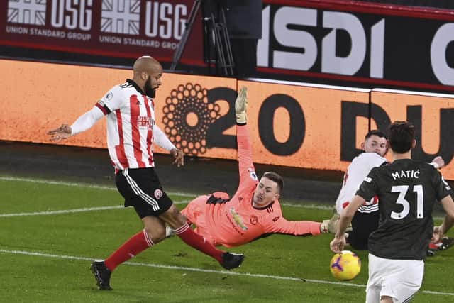 Sheffield United's David McGoldrick, left, shoots to score, as Manchester United's goalkeeper Dean Henderson, center tries to stop him, during the English Premier League soccer match between Sheffield United and Manchester United at the Bramall Lane stadium in Sheffield, England, Thursday, Dec. 17, 2020. (Laurence Griffiths/Pool via AP)