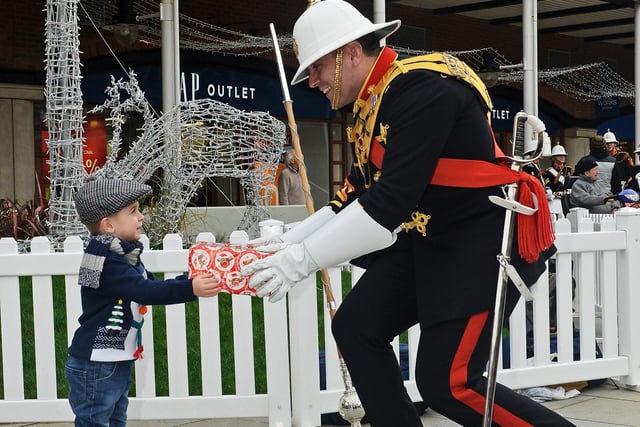 A member of the Band of Her Majesty’s Royal Marines Portsmouth hands a present to a youngster during a Christmas event at Gunwharf Quays.