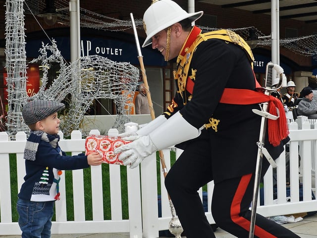 A member of the Band of Her Majesty’s Royal Marines Portsmouth hands a present to a youngster during a Christmas event at Gunwharf Quays.