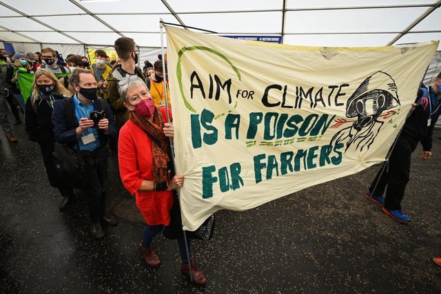 Protesters hold up a banner which reads 'Aim for climate is a poison for farmers'