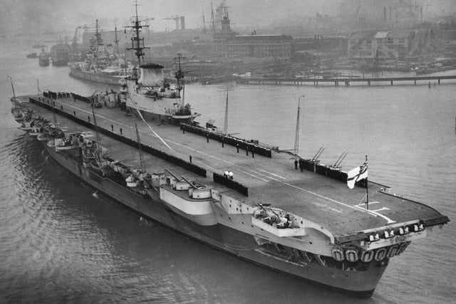 Officers and crew line the flight deck of HMS Indefatigable as she returns to Portsmouth following service in the Far East in 1946.