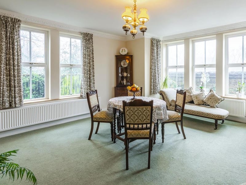 With carpet to flooring, central heating radiator, feature fireplace with surround and dual-aspect windows to the front and side elevation.