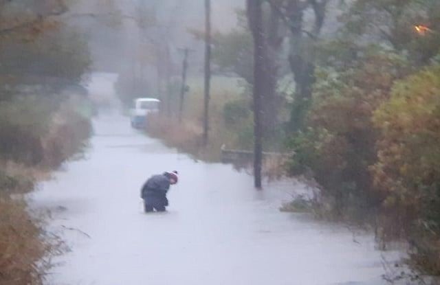 A man thigh deep in flood waters at the entrance to the RSPB Dumfries and Galloway Mersehead reserve, just off the A710.