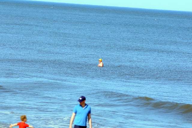 People can be seen keeping their distance while cooling off in the sea.