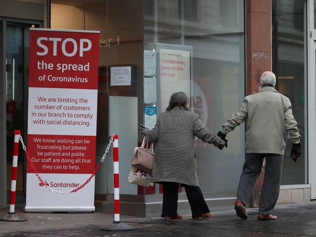 A couple walk past a coronavirus advice sign outside a bank on Argyle Street in Glasgow city centre the morning after stricter lockdown measures came into force