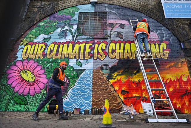 Artists paint a mural, part of the Grantham Climate Art Prize organised by the Grantham Institute - Climate Change and the Environment at Imperial College London on a wall next to the Clydeside Expressway