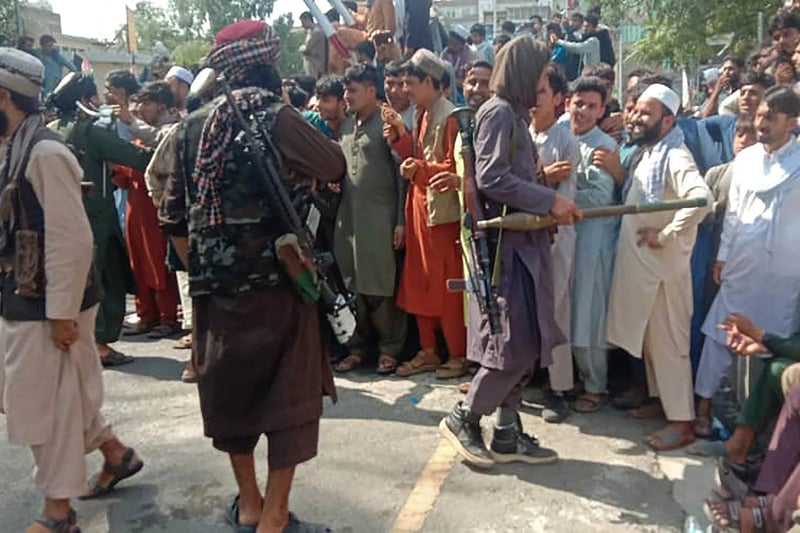 Taliban fighters and local people are pictured along the street in Jalalabad province