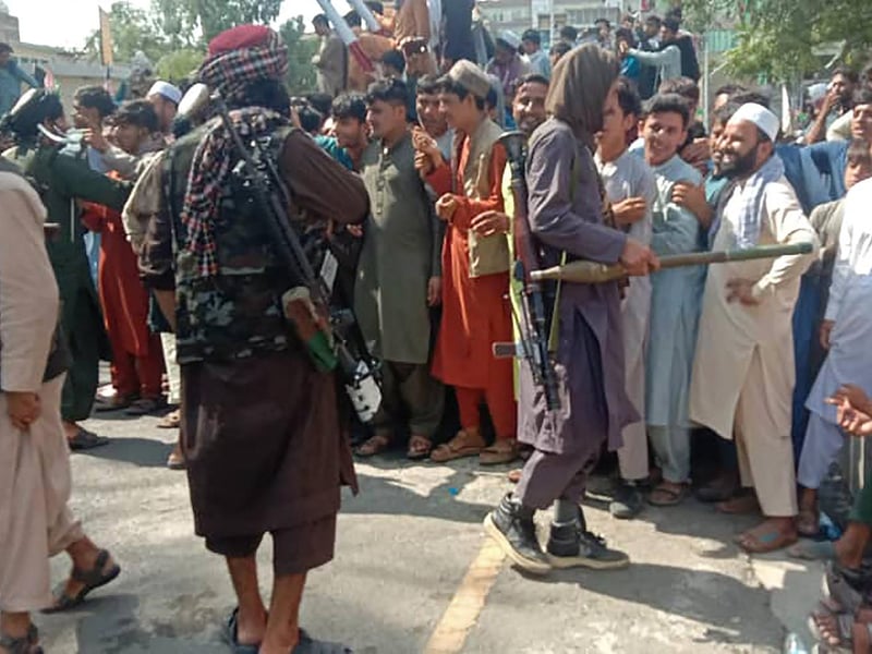 Taliban fighters and local people are pictured along the street in Jalalabad province