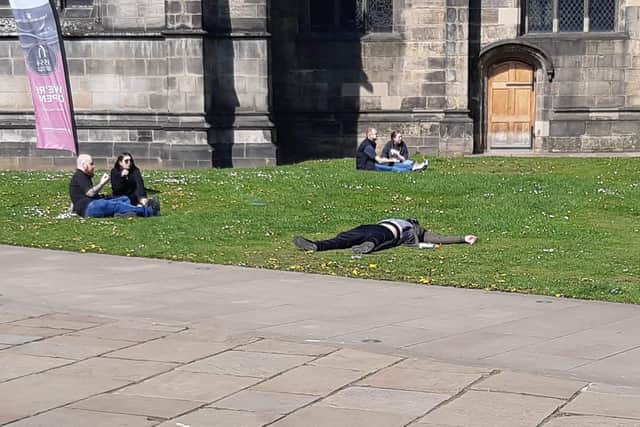 A man lies outside Sheffield Cathedral amid people relaxing.