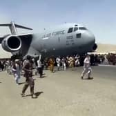 Hundreds of people run alongside a U.S. Air Force C-17 transport plane as it moves down a runway of the international airport, in Kabul, Afghanistan, Monday, Aug.16. 2021. Thousands of Afghans have rushed onto the tarmac at the airport, some so desperate to escape the Taliban capture of their country that they held onto the American military jet as it took off and plunged to death. (Verified UGC via AP)