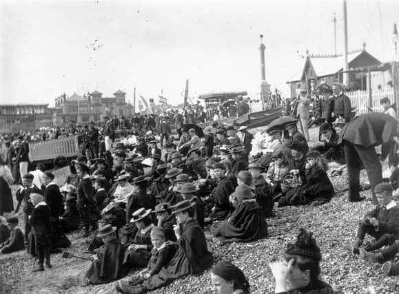 This photo is from circa 1895 and it shows a crowd mainly of children, wearing hats and warm clothing, sit on stony Southsea beach looking out to sea. Photo by F J Mortimer/Hulton Archive/Getty Images