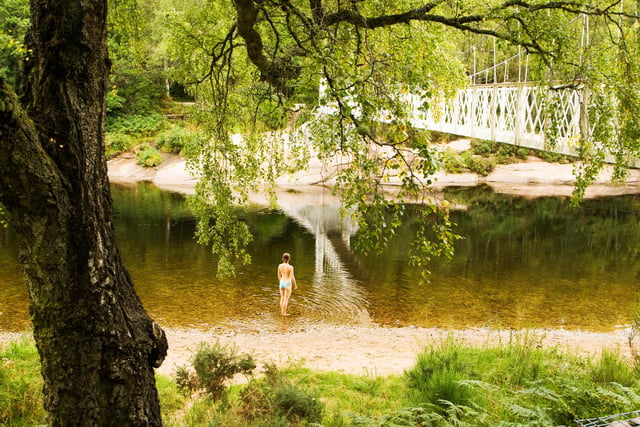 The sandy banks and flat rocks close to this pretty suspension bridge  are popular in the summer for picnics and swimming.
