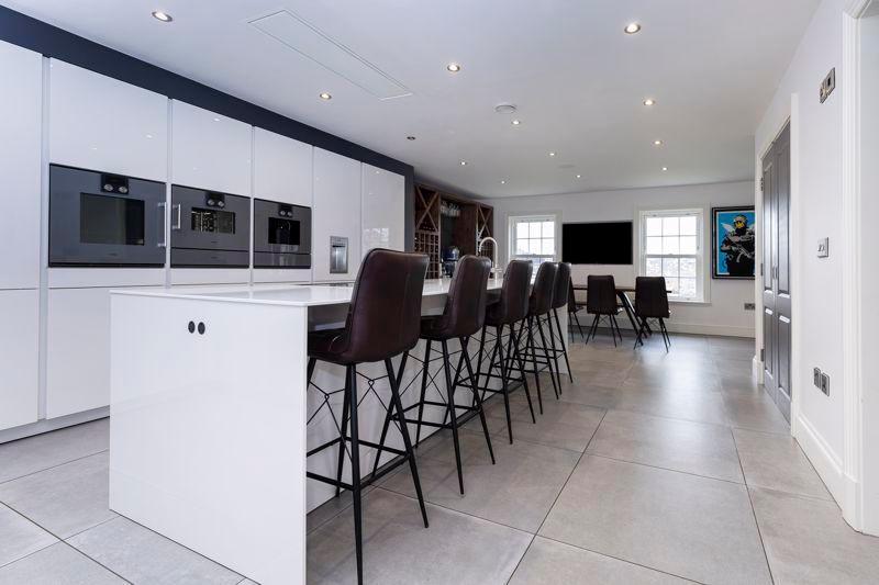 The stunning kitchen houses sleek white Siemetic units and is equipped with Gaggenau appliances including oven, two warming drawers, coffee machine, dishwasher, fridge and freezer.