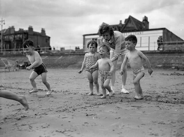 A mother persuades her little boy to go into the sea at Portobello Beach during the fair fortnight in 1961.