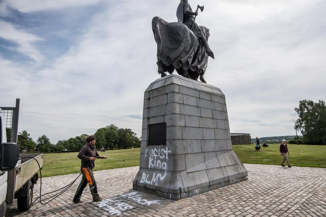 Graffiti on the plinth that supports the statue of King Robert says: “Racist King. BLM. Black Lives Matter.”