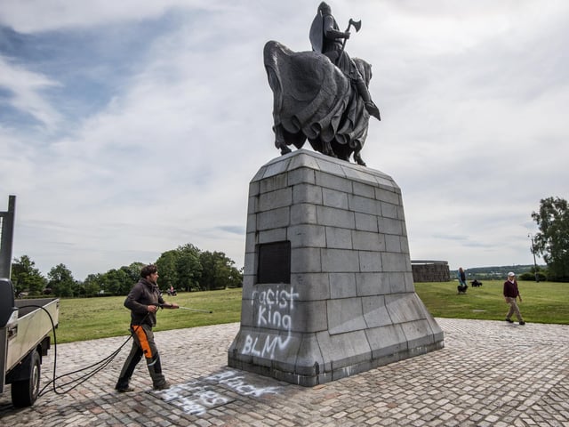Graffiti on the plinth that supports the statue of King Robert says: “Racist King. BLM. Black Lives Matter.”