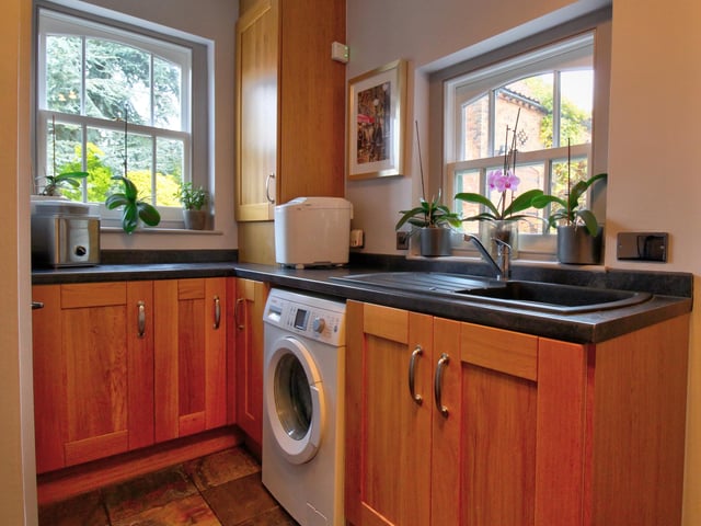 Having fitted wall and base level units, under unit plumbing for washing machine, inset sink and drainer, cupboard which houses the central heating boiler, two windows to rear and wall mounted radiator.