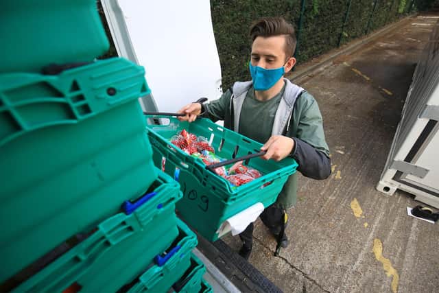 Ash Cooke stacking crates at The Food Works base in Handsworth, Sheffield, where people can pick up surplus supermarket stock over Christmas