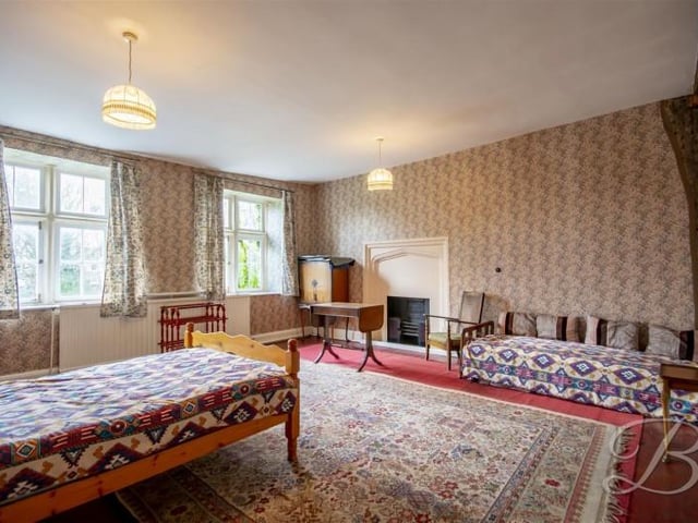 This large bedroom has a lovely fireplace and some exposed wood.
