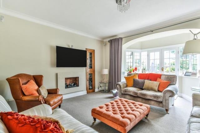 The living room has a wall-hung electric fireplace, rear facing French doors opening onto the vast rear garden, and access through to the dining room and kitchen.