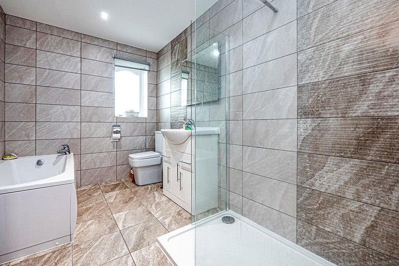 Fully tiled bathroom with a three piece suite in white.