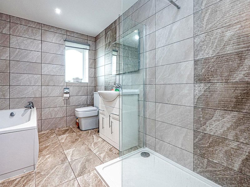 Fully tiled bathroom with a three piece suite in white.