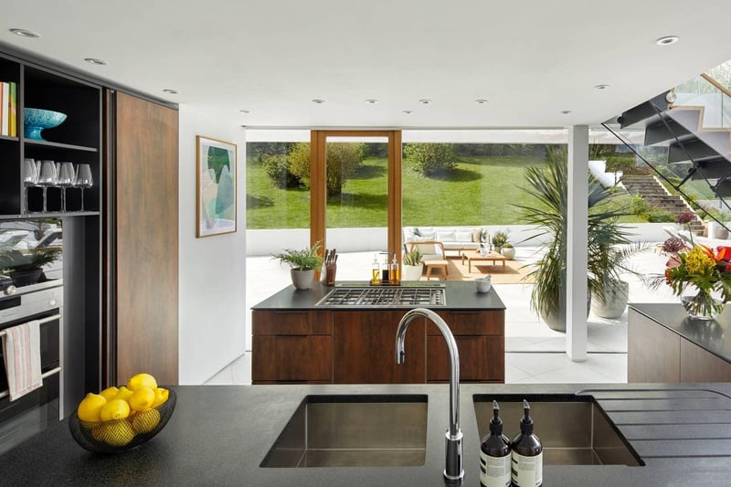 The open-plan fully fitted kitchen-dining area, with sliding glass doors, leads out to an infinity pool and vast sea views .