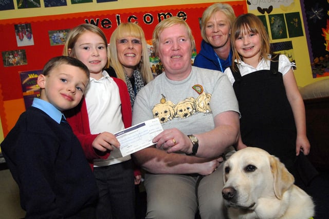 Staff and youngsters from the Ashfield Playcare Scheme present Mrs Kathleen Patten and her dog Vogue with a £256.65 cheque for the Guide Dogs for the Blind Association following  a fund raising green day and Halloween event.  Pictured from left, are Matthew Anderson, Lily Sheridan, manager Ann Buchanan, her assistant Tracy Bolger and Charlotte Wright.