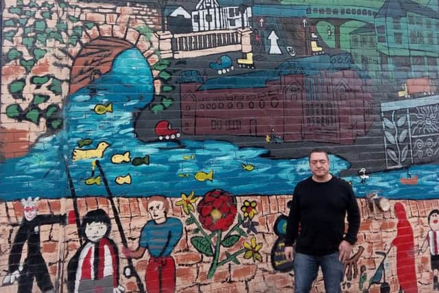 Nevio Bagnoli beside a mural on the wall of his hairdressing salon in Heeley